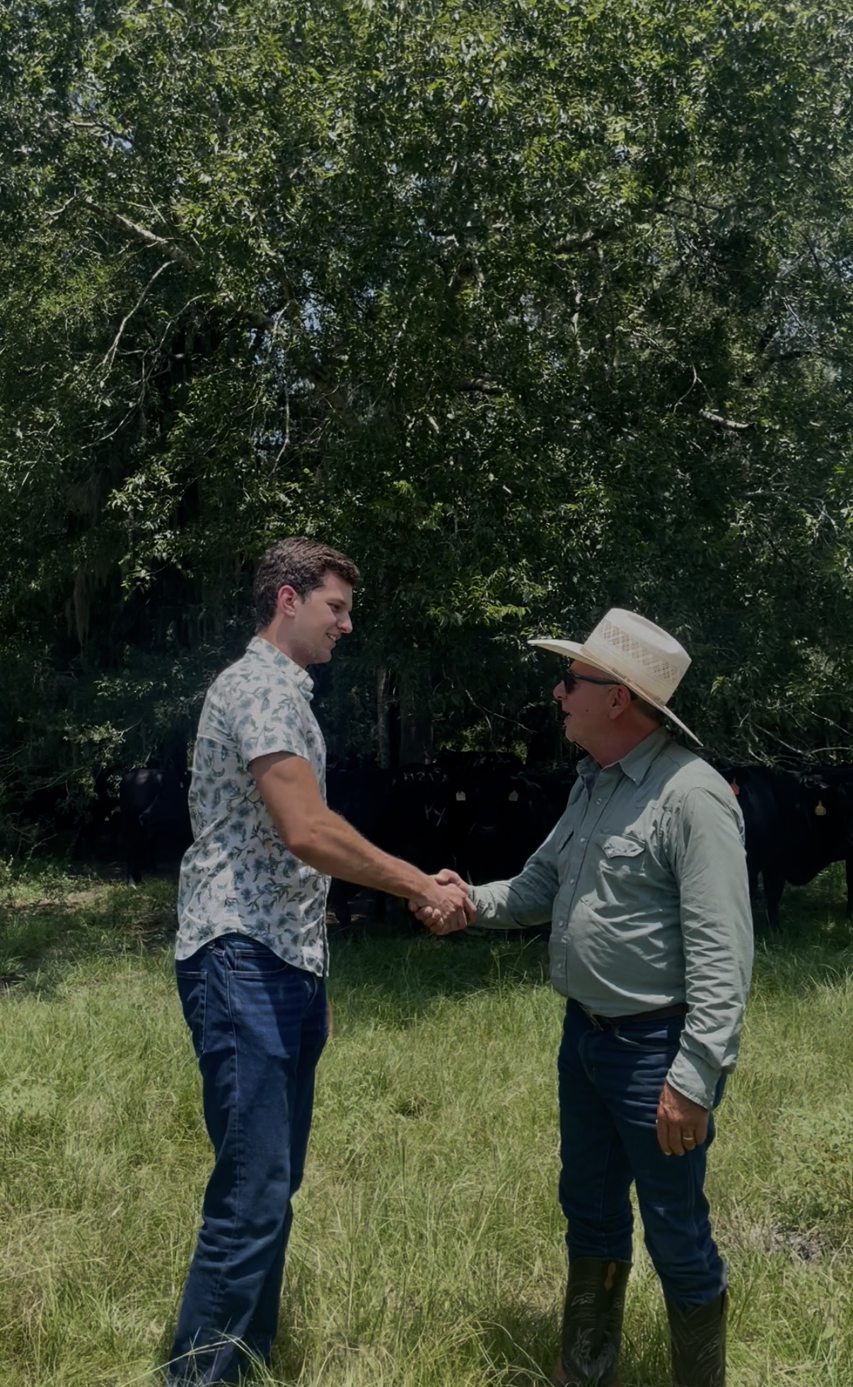 Michael Borchers shaking hands with a Winch family rancher in the pasture at Winch Ranch, Montgomery, Texas